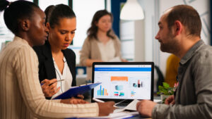 busy-multicultural-diverse-employees-analysing-annual-financial-statistics-sitting-desk-front-laptop-holding-documents-searching-business-solutions-team-businesspeople-working-company